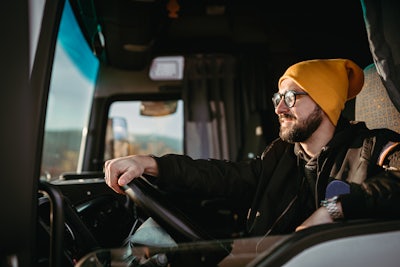 En man i gul mössa kör en lastbil.