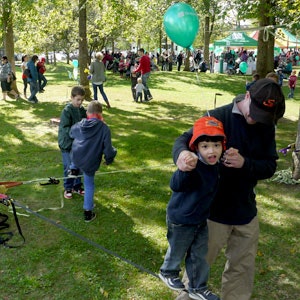 Enfant qui fait ses premiers pas sur une slackline, accompagné d'un adulte