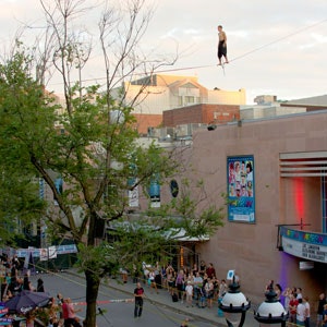 Person on a urban highline, over a crowd