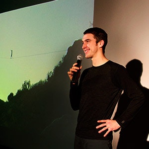 Man on stage with a microphone, presenting highlining