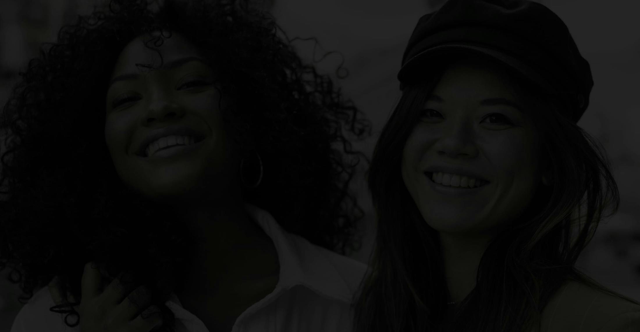 Dark Image of Two Young Women in the City, Smiling into the Camera