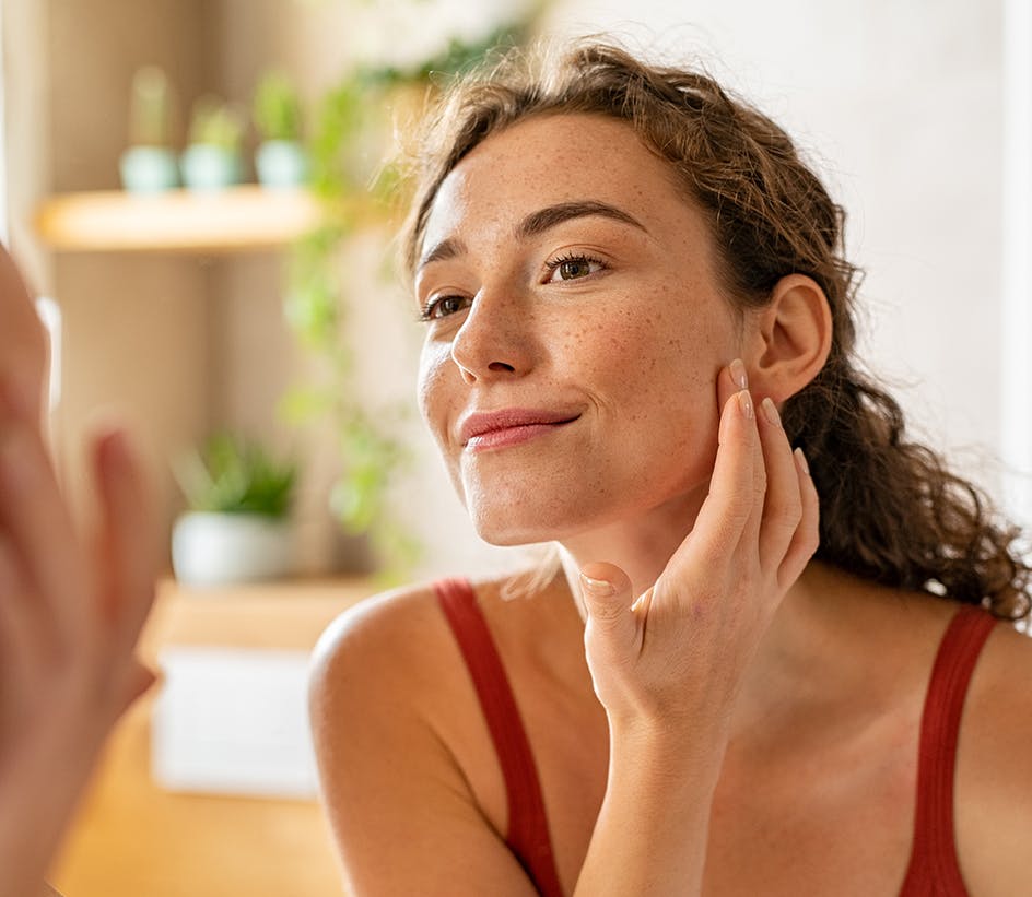 Curly-haired woman looking at her face in the mirror