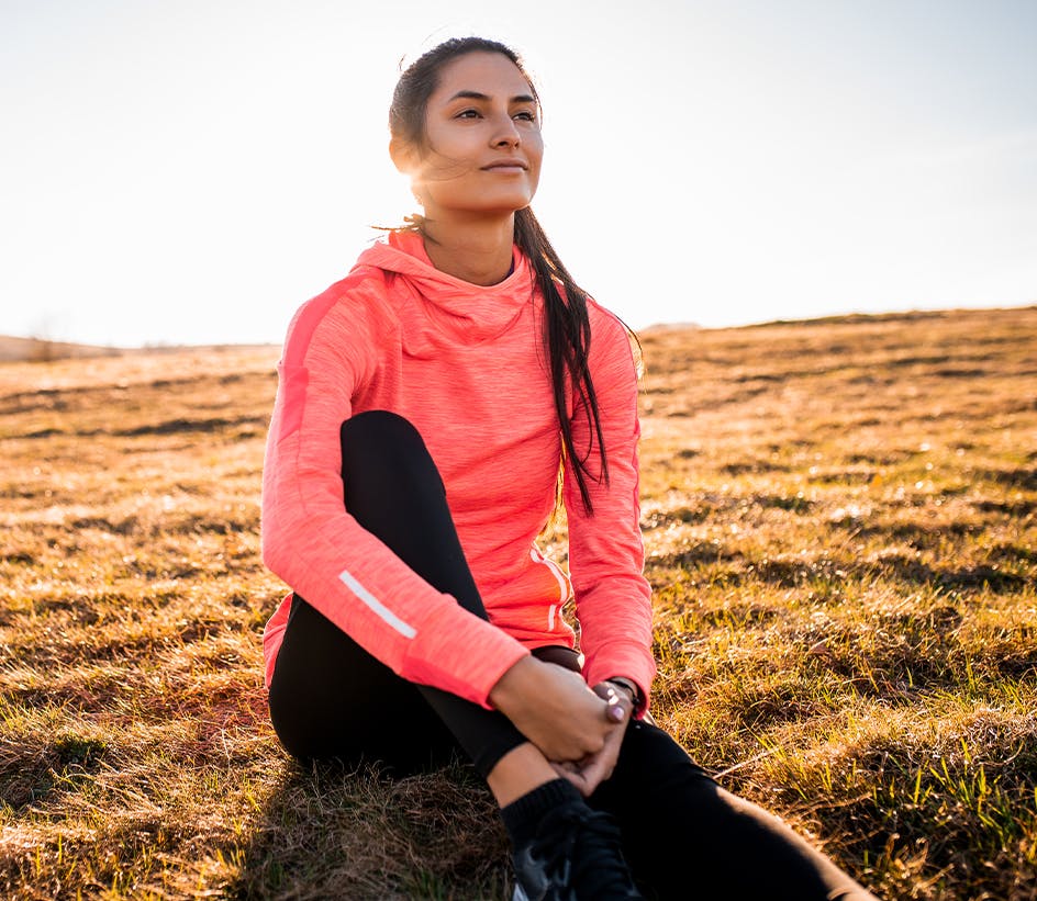 Woman wearing a bright pink sweatshirt sitting in grass