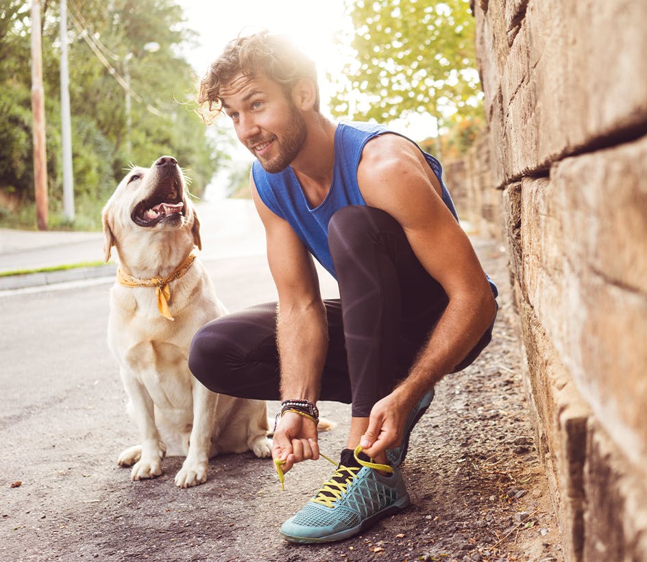 man tieing his shoe with his dog