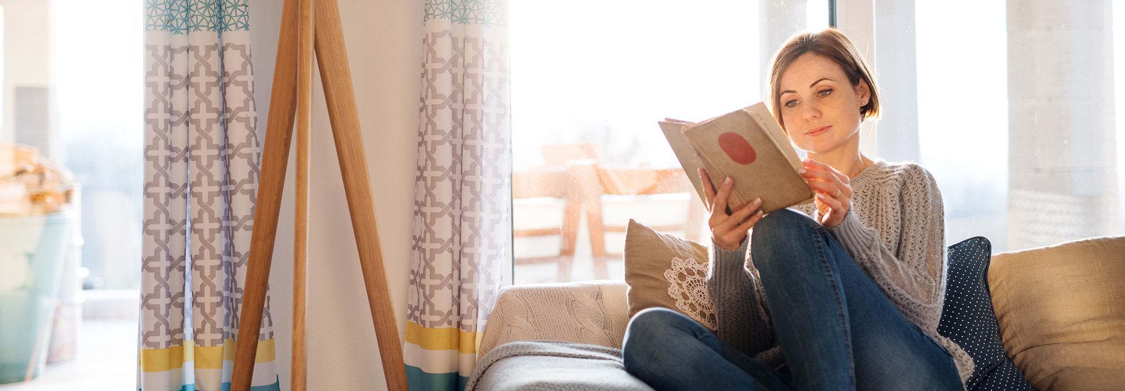 Woman wihtout migraine reading a book on a couch