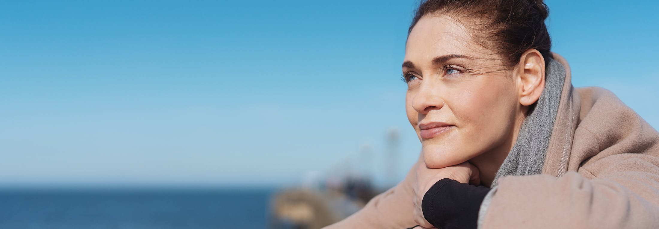 Woman near body of water staring off in the distance
