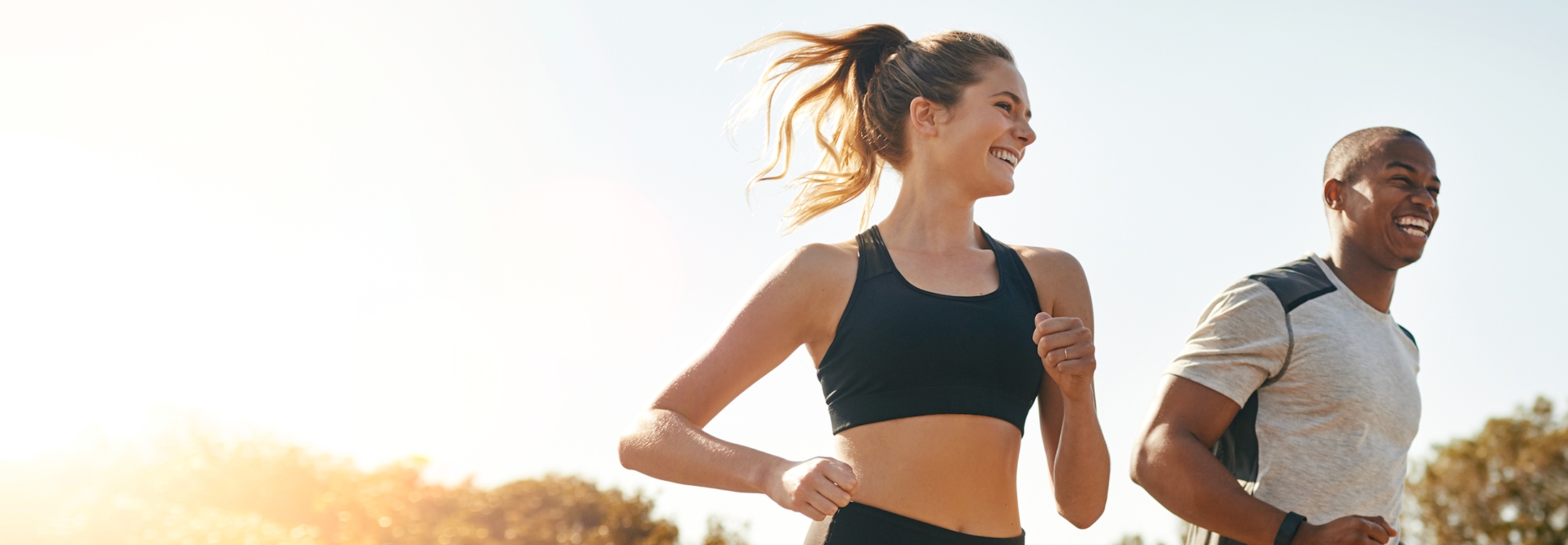 Man and woman smiling while running outside