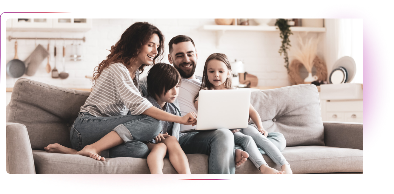 Couple with 2 kids sitting on the couch and using laptop