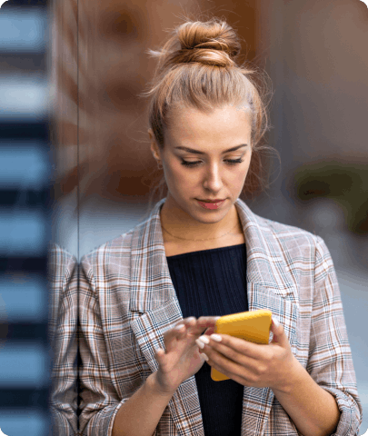 A woman is focused on her phone, her eyes fixed on the screen as she engages with its content.