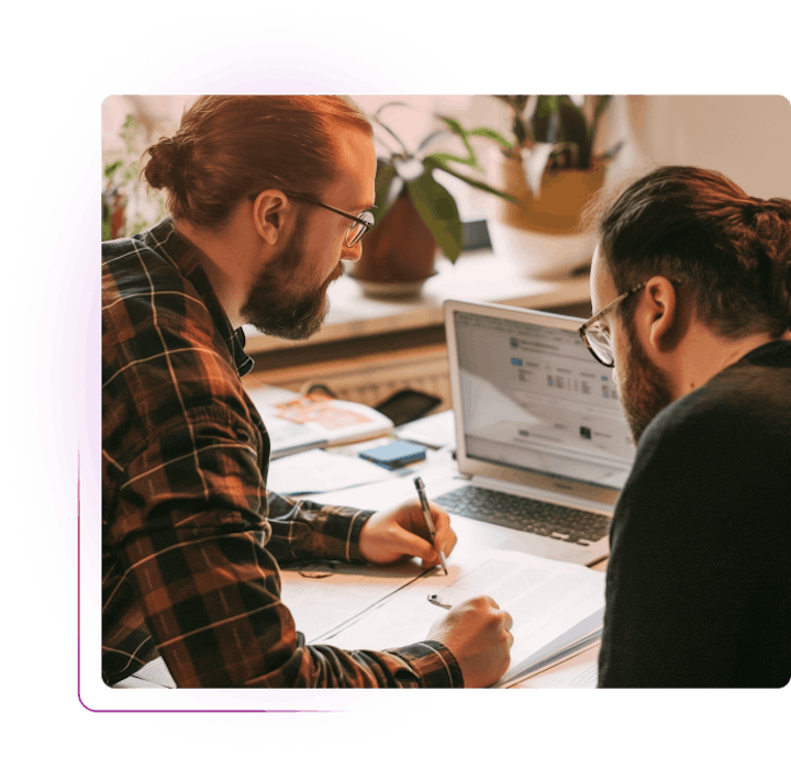 Two men discussing over laptop and a piece of paper