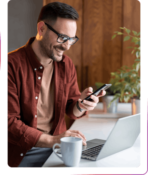 young guy using phone and laptop smiling