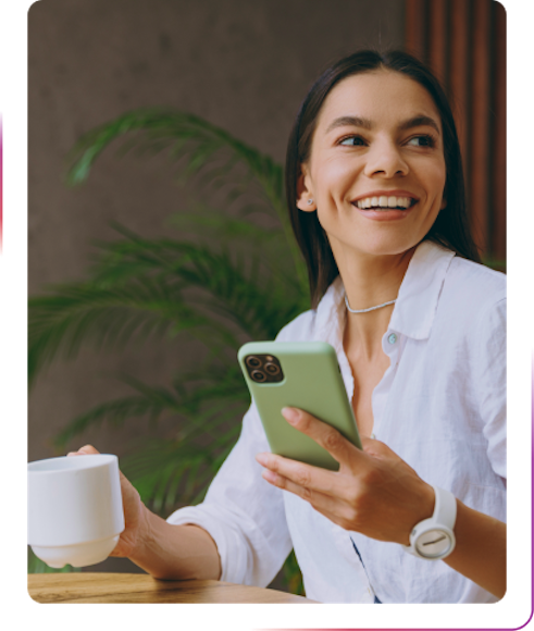 smiling woman using a phone and drinking coffee