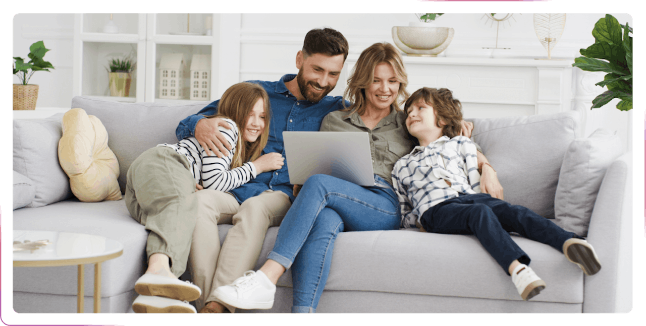 family sitting on the sofa using laptop and smiling