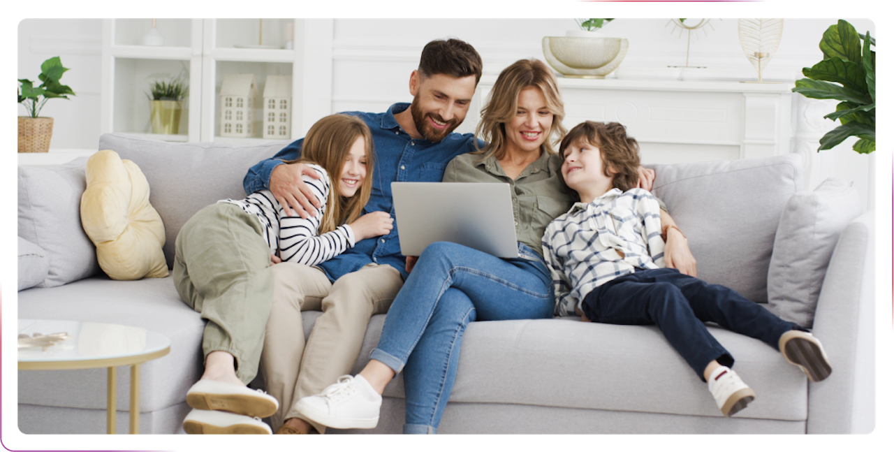 family sitting on the sofa using laptop and smiling