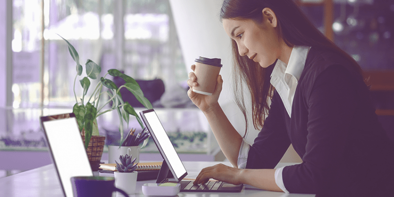 Woman drinking coffee and using laptop