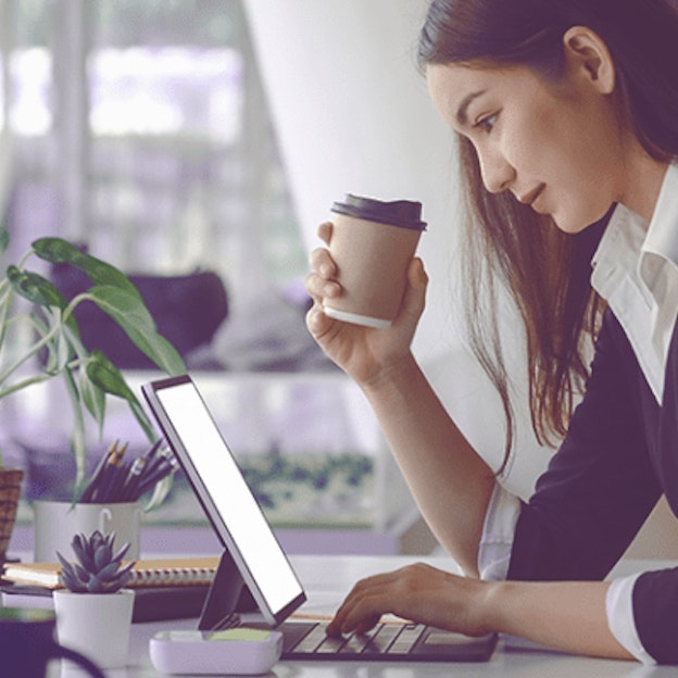 Woman drinking coffee and using laptop
