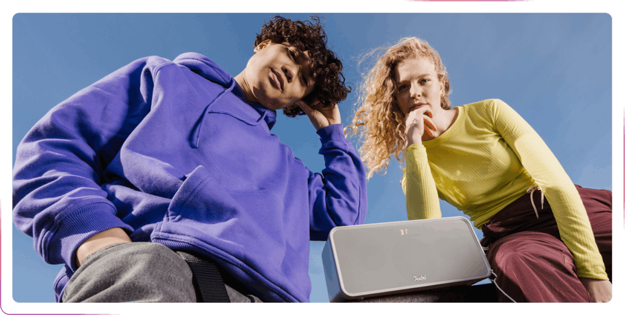 young couple posing next to the gray speaker