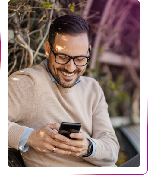 a man with glasses smiles using phone