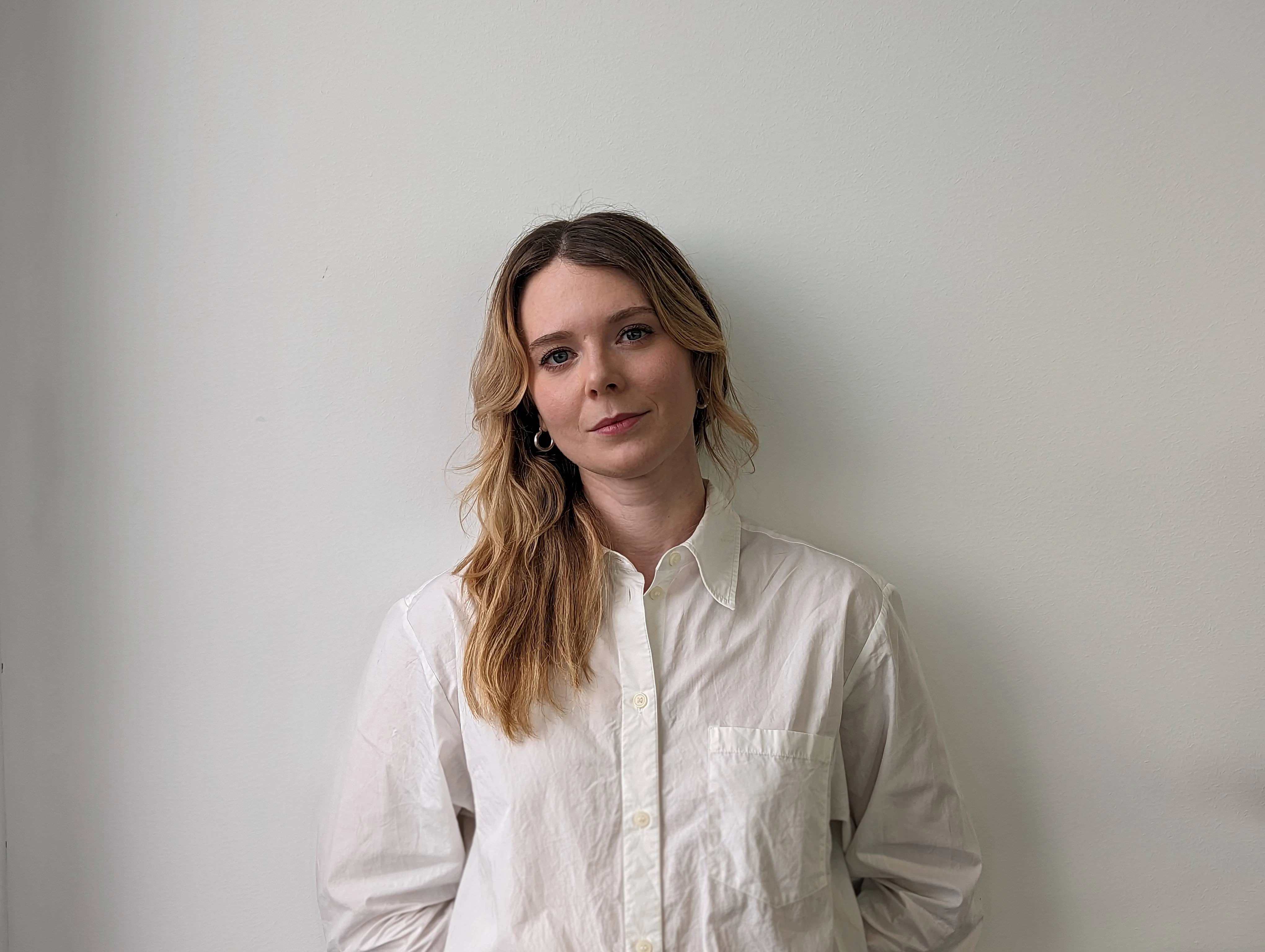 A portrait of Hanna Rönnqvist, female in her 30s in front of a off-white wall