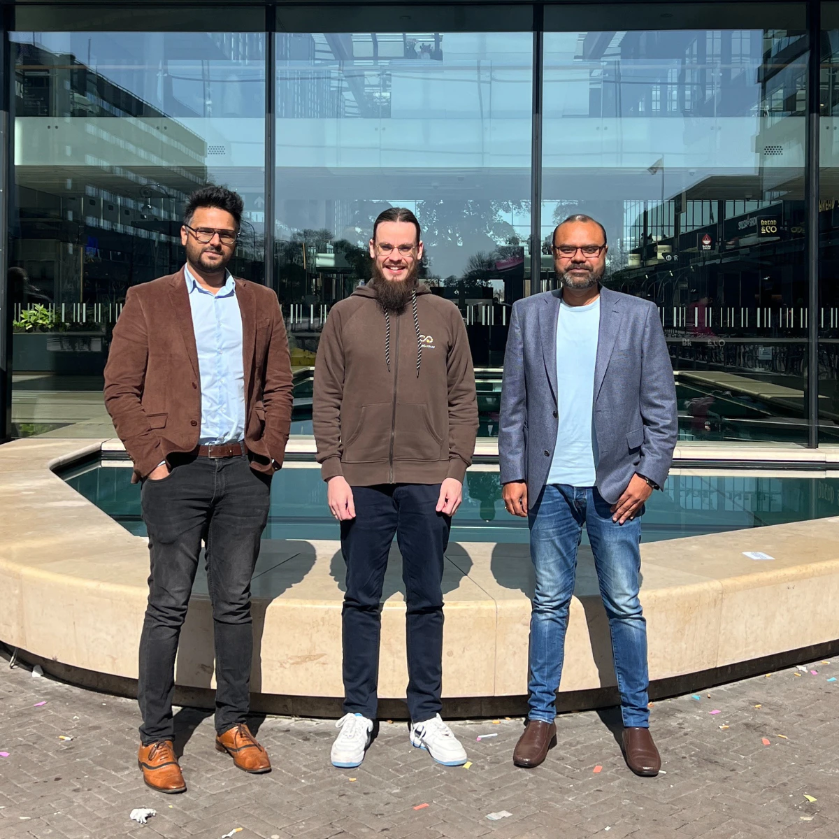 Three men standing outside in front of office building