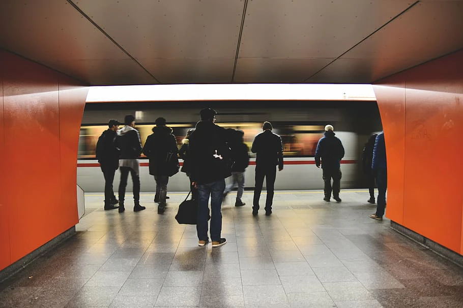 Folk stående på tunnelbana perrongen med tåg som har ankommit