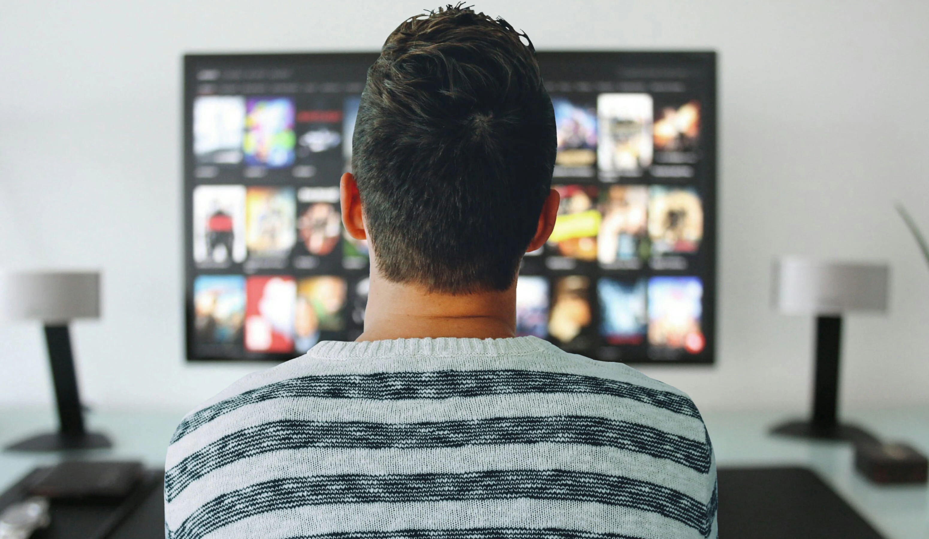 Man viewed from behind watching a screen