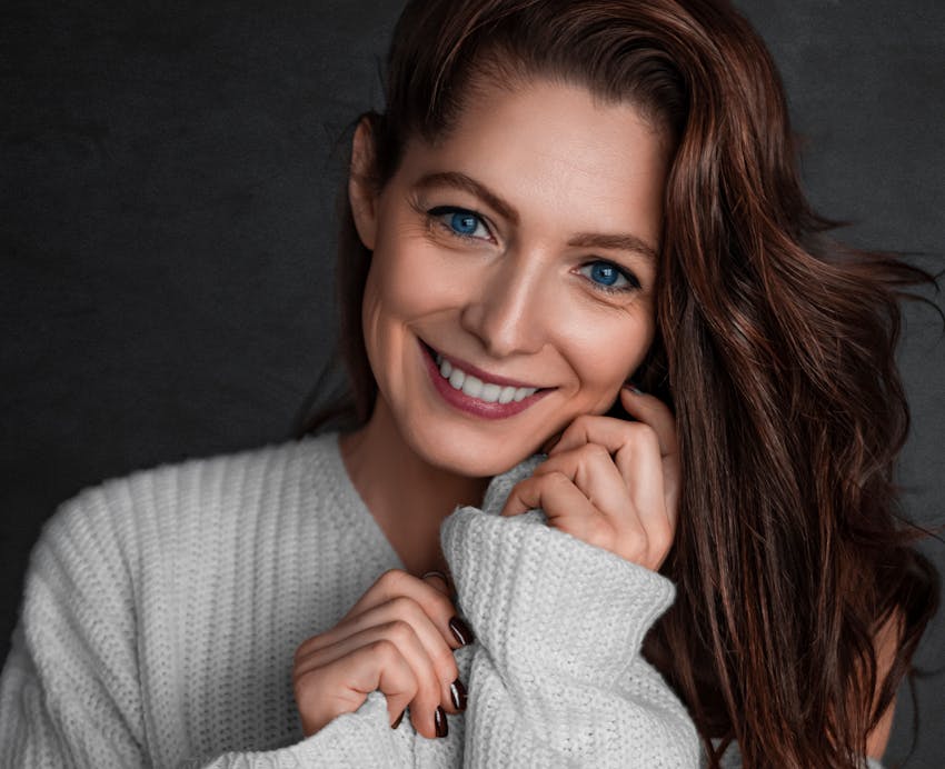 Woman with red hair and light gray sweater on