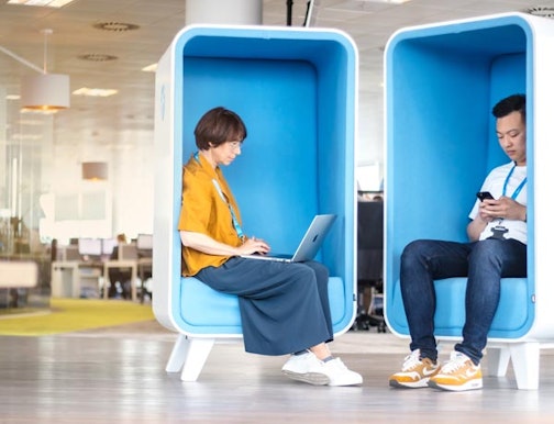 Office workers using laptops in a breakout area