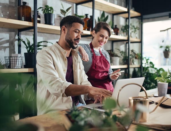 Peninsula Group Limited - Two employees in a flower shop looking at a laptop and smiling