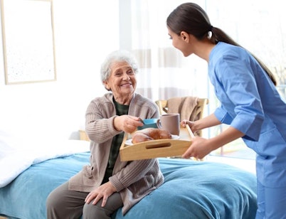Peninsula Group Limited - A care worker serving a patient her breakfast