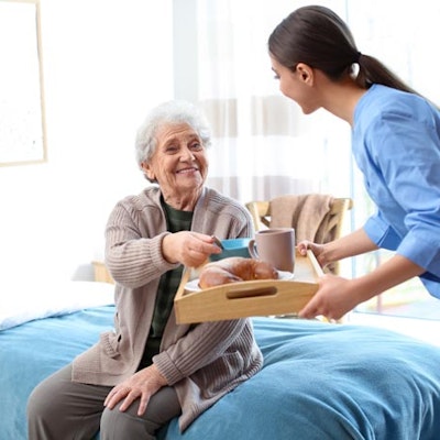 Peninsula Group Limited - A care worker serving a patient her breakfast