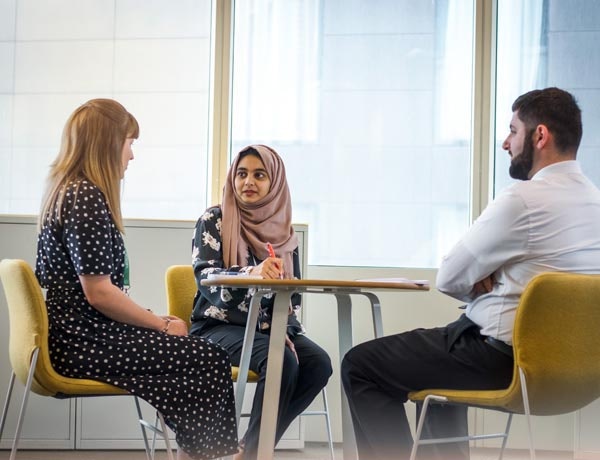 Three people sitting at a meeting room table together