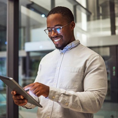 Peninsula Group Limited - An employee smiling as they check their tablet in a office setting
