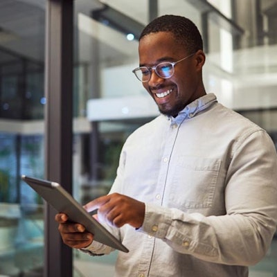 Peninsula Group Limited - An employee smiling as they check their tablet in a office setting