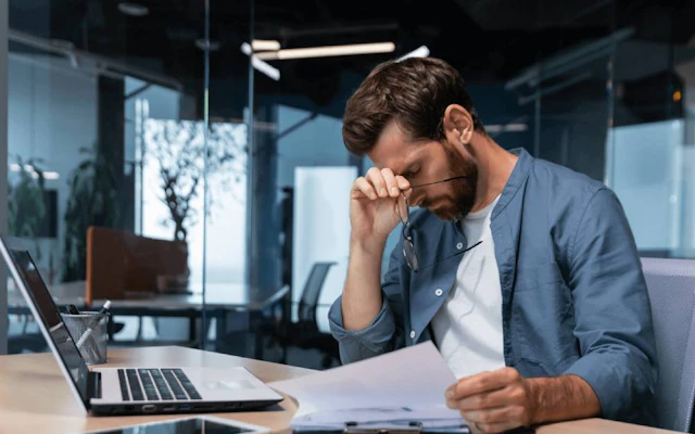 Person working on laptop looking stressed