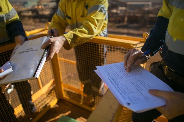 Workers in hi-vis jackets completing a risk assessment outside