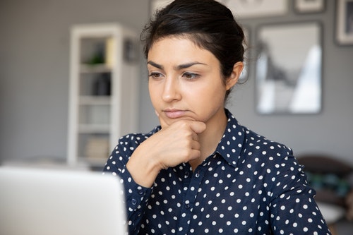 a woman looking at her laptop thoughtfully