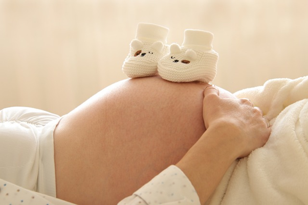Someone who is pregnant with baby shoes on their stomach.