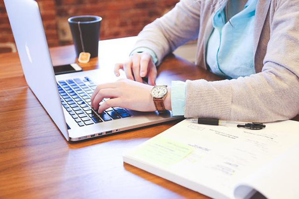 Someone using a laptop to contact an employee off sick.
