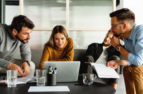 Employees meeting around a laptop in a breakout area