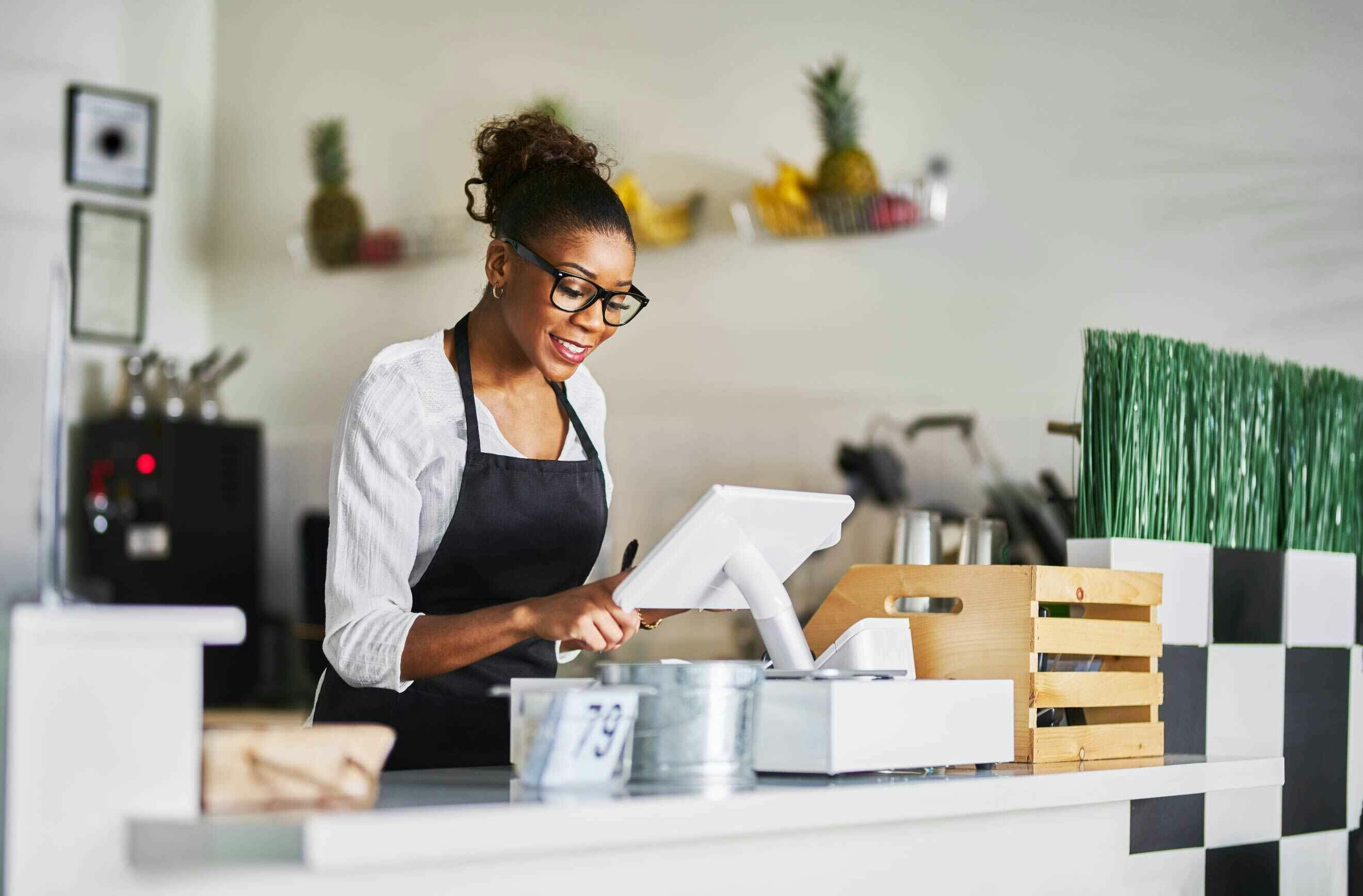 A woman working on an EPOS system in a cafe