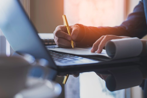 someone making notes on a computer