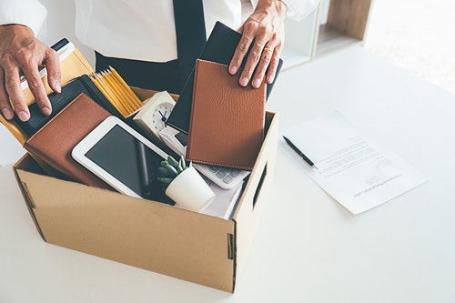 someone filling a box with various desk items