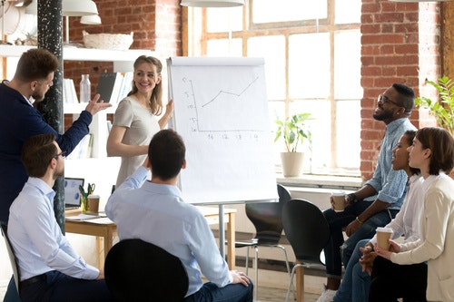 A group of people sat around a flip chart looking at graphs