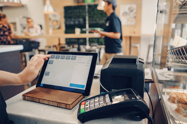 A shop worker using a tablet as a till next to a card machine