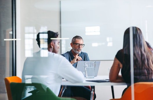 Three workers sat around a table in a meeting.