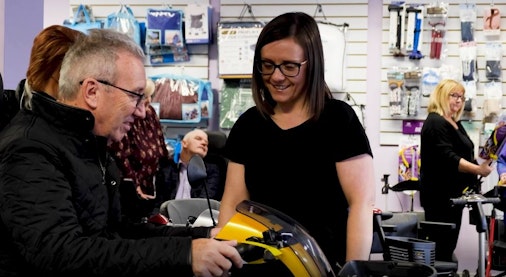 A woman helping a customer on a mobility scooter.