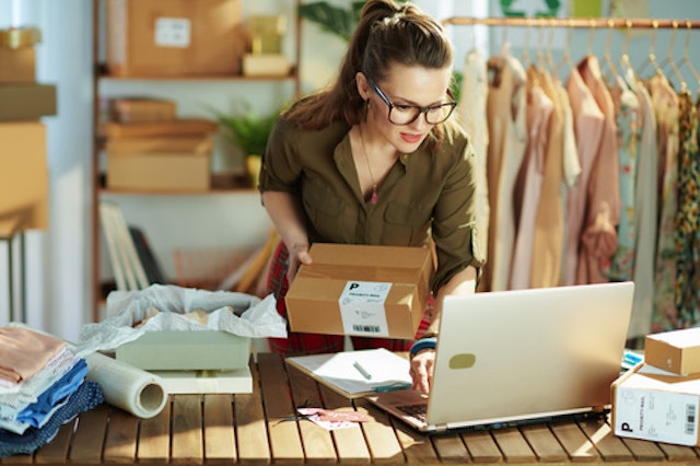 a woman holding a package while working at a desk