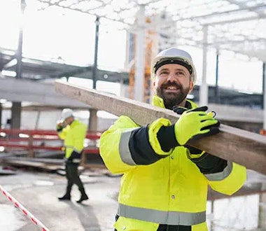 A construction worker holds a metal beam.