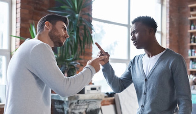 Two men looking at eachother in a workplace environment with one pointing his finger